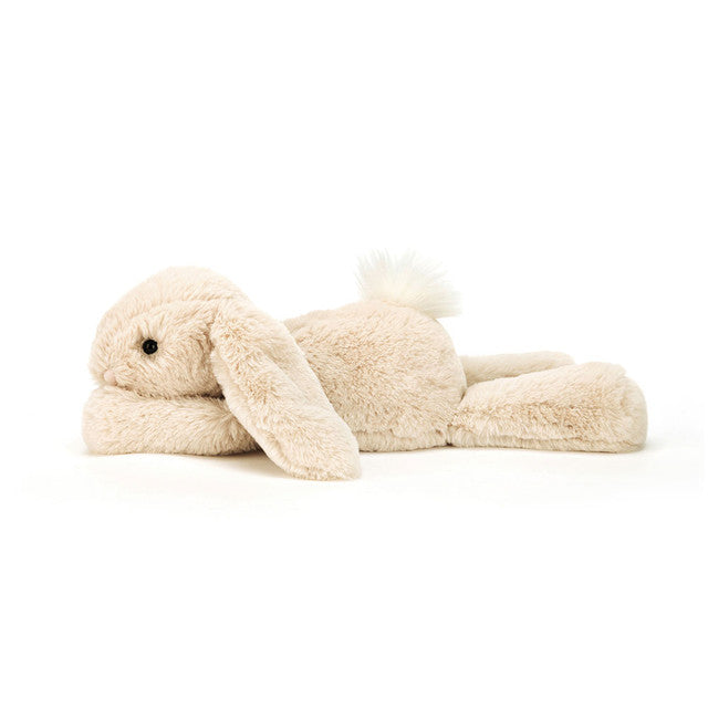 Adorable Smudge Rabbit by JellyCat, lying comfortably on its stomach with a fluffy tail and relaxed posture.