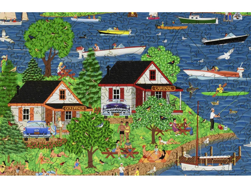 A close-up of colorful cottages by the lake, showcasing the words 'Goldfinch' and 'Carnival', from the 'Summer at the Lake' puzzle by Liberty Puzzles.