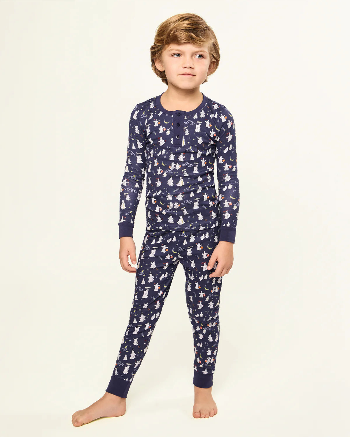 Child confidently modeling the Kids Pima Snug Fit Pajama in Spooky Slumber by Petite Plume, showing fun Halloween ghosts against a starry backdrop.