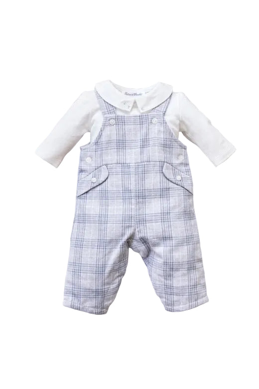 Baby outfit with blue plaid overalls and white shirt on a beige surface