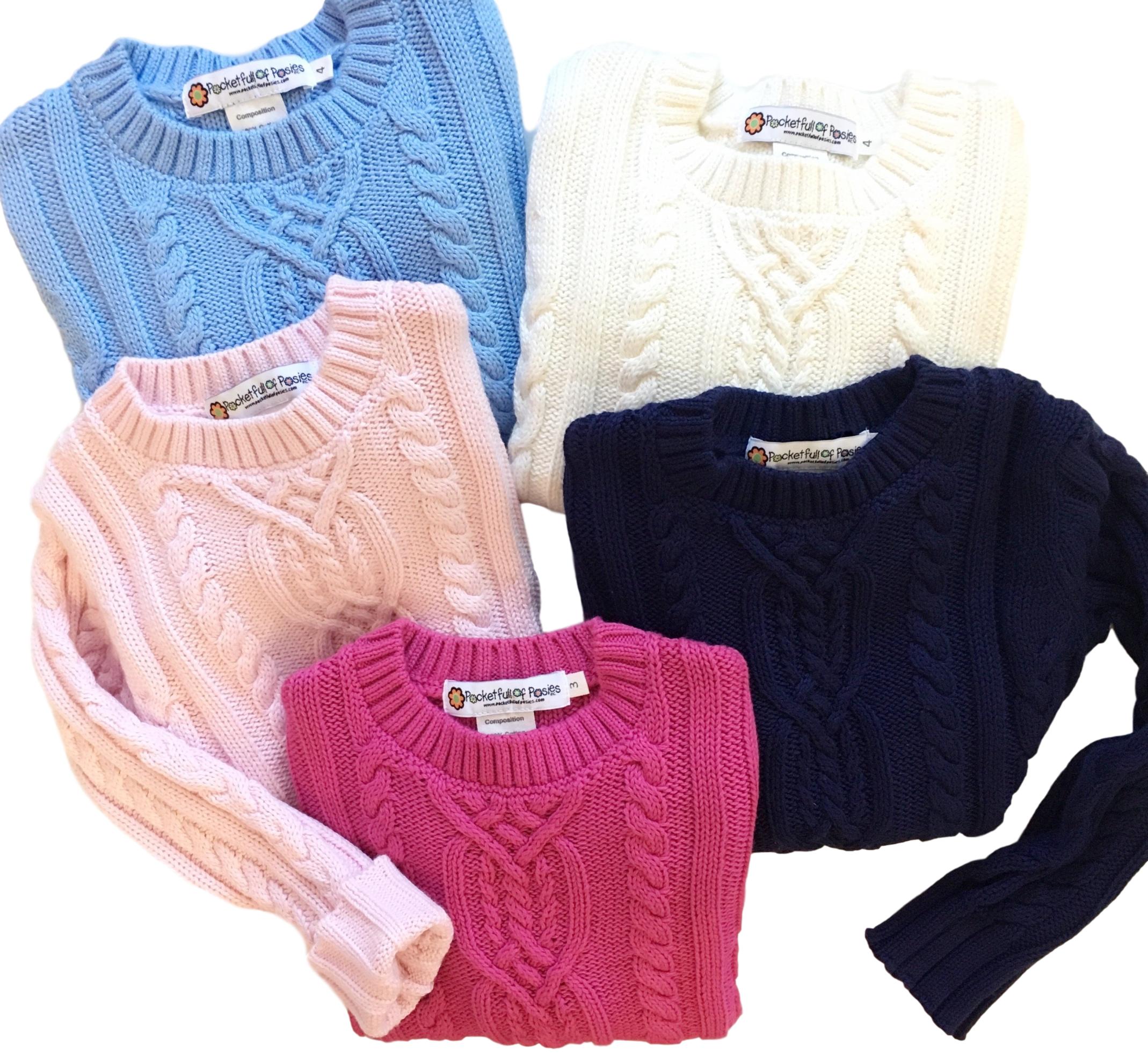 A collection of colorful cable knit sweaters in various shades including blue, pink, white, navy, and dark pink from Pocket Full of Posies. Perfect for cozy layers, these cable knit sweaters add style and warmth to any outfit. Explore the Pocket Full of Posies collection.