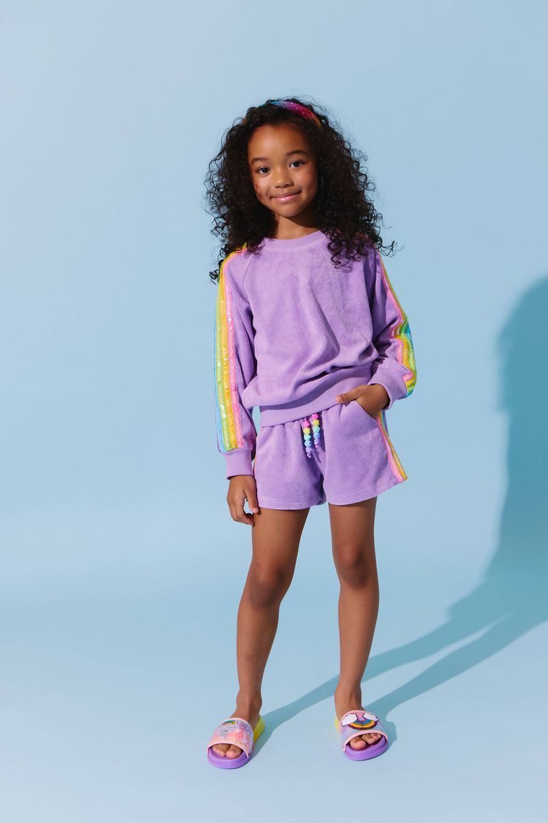 Young girl in the Lavender Rainbow Sequin Stripe Short Set by Lola and the Boys, showcasing a cozy lavender sweatshirt and vibrant rainbow short set, ideal for playdates.