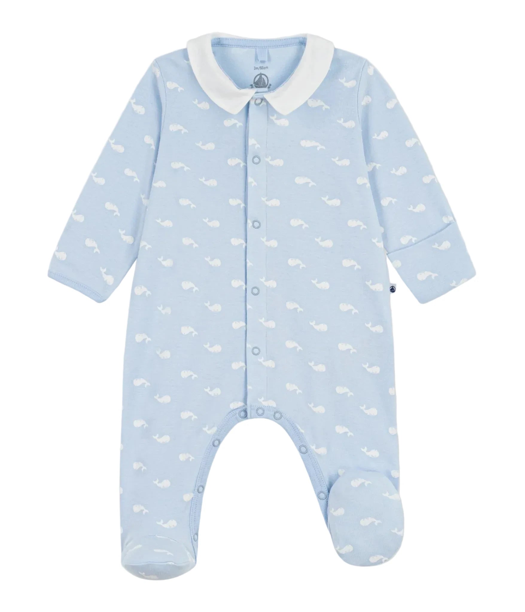 A baby footed one-piece sleeper in light blue with a white whale print, featuring a white collar and snap-button front, shown on a light gray background.