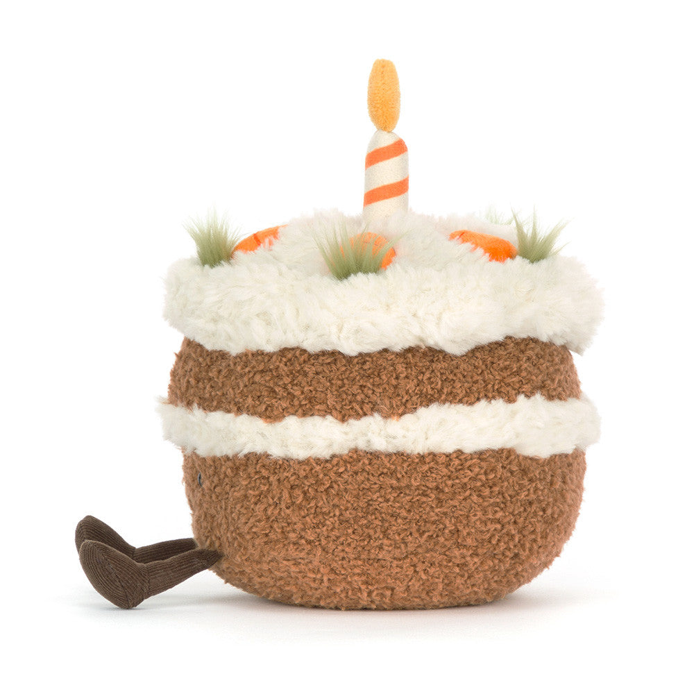 Side view of Amusables Carrot Cake by JellyCat showcasing its round shape, soft plush material, and playful design elements like a candle and happy face.