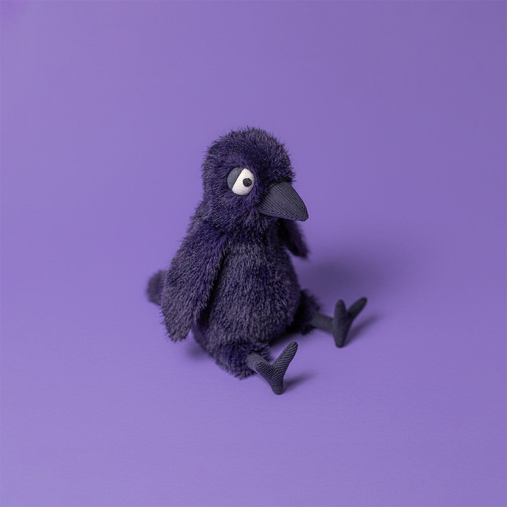 Hocus Crow plush surrounded by Halloween decorations, ideal for year-round whimsy.