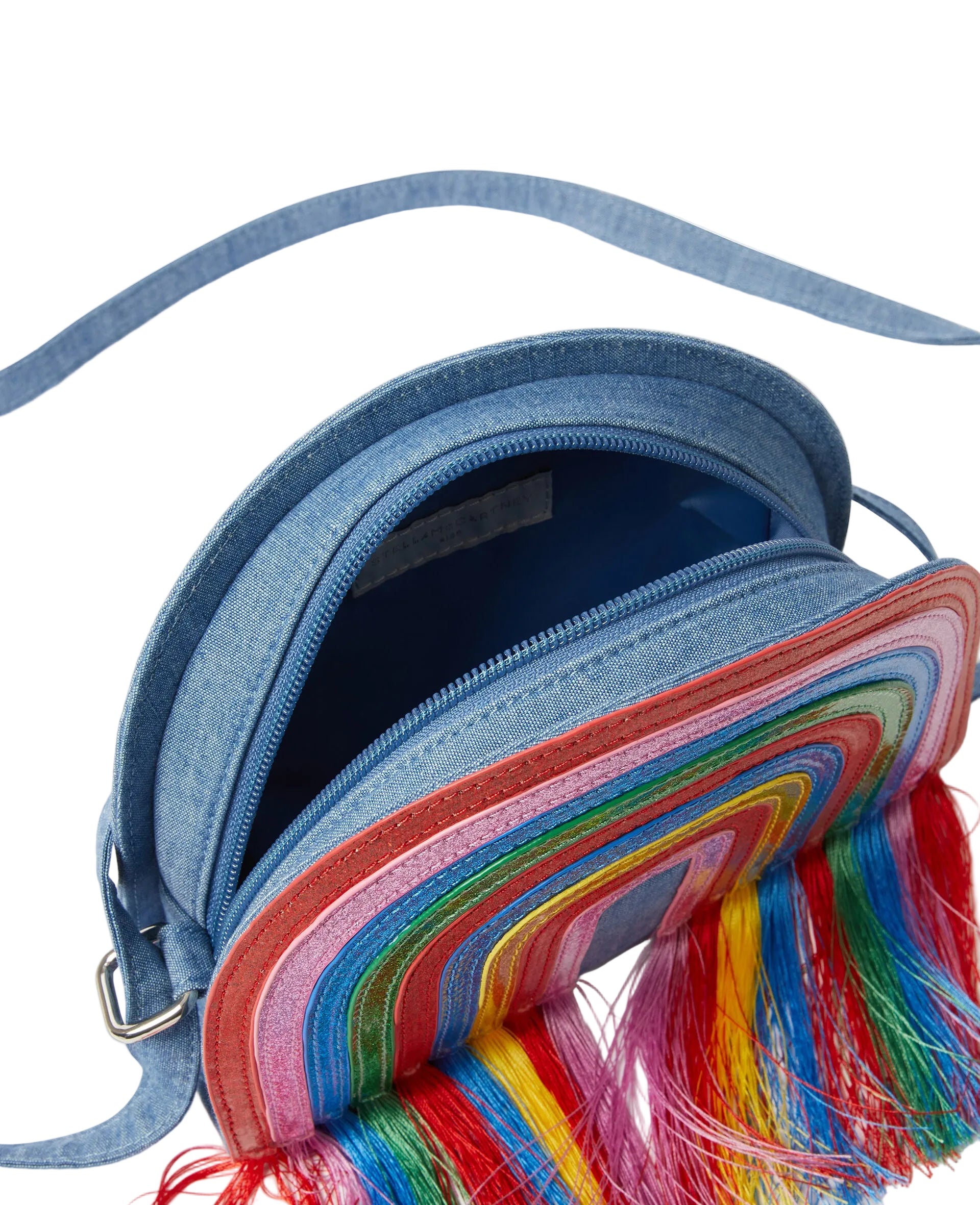 A close-up of a blue denim crossbody bag with a colorful rainbow fringe detail and a long blue strap, shown on a light gray background.