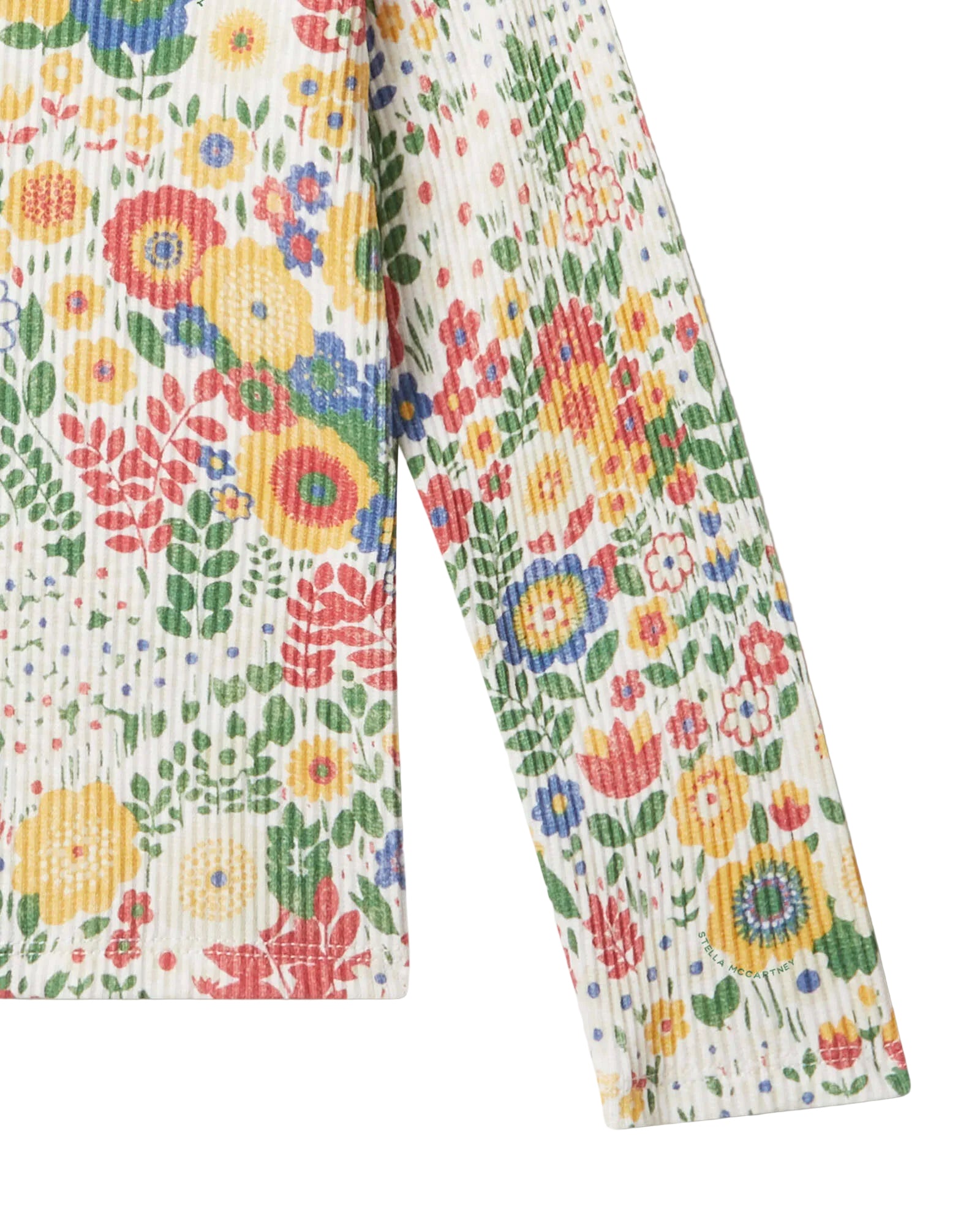 A close-up of a long-sleeve garment with a colorful floral print on a textured off-white fabric, laid flat against a light background.