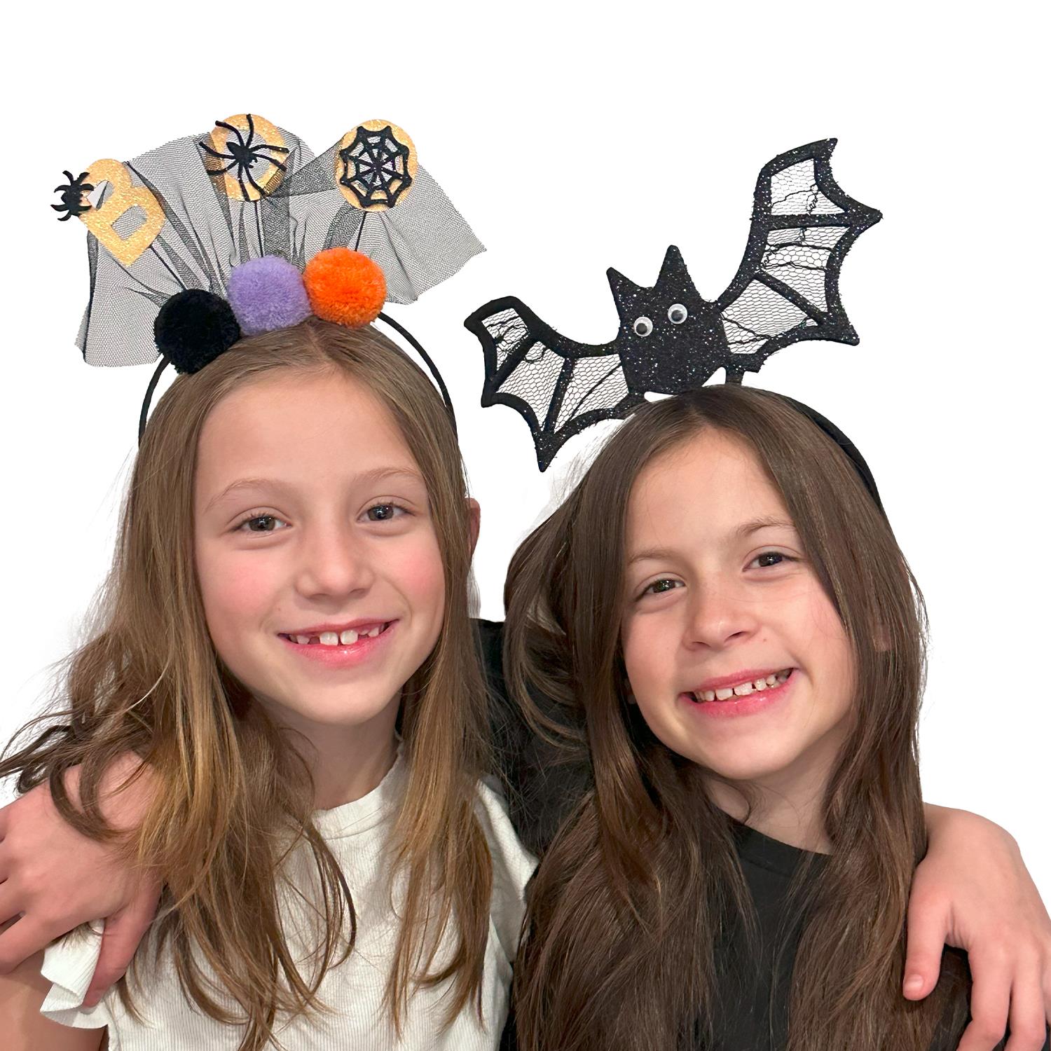 Two girls wearing stylish Halloween headbands, one with a bat and the other with a festive design, showcasing fun and festive elements from Cupcakes and Cartwheels. Great for celebrating Halloween!