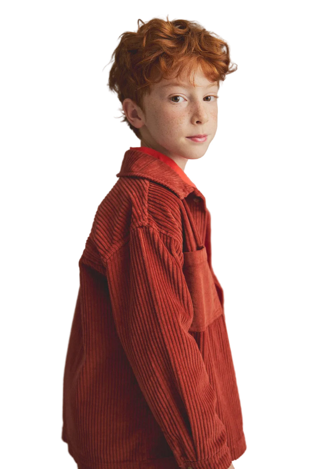 Young boy wearing a red textured coat against a gray background