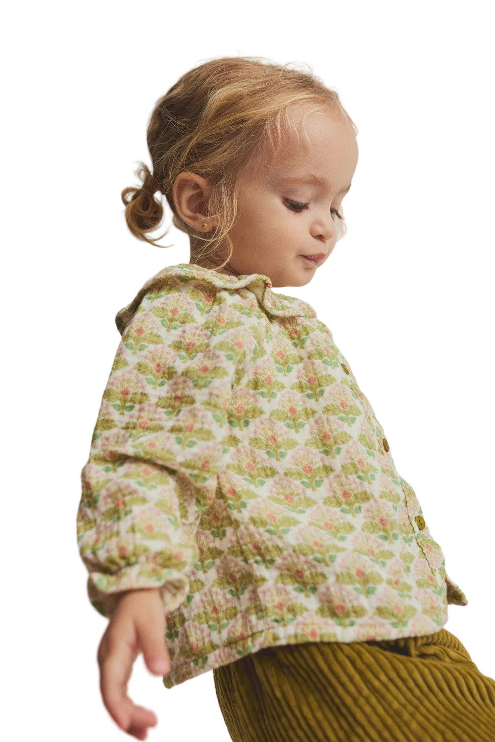 Child wearing a floral jacket and green pants on a plain background