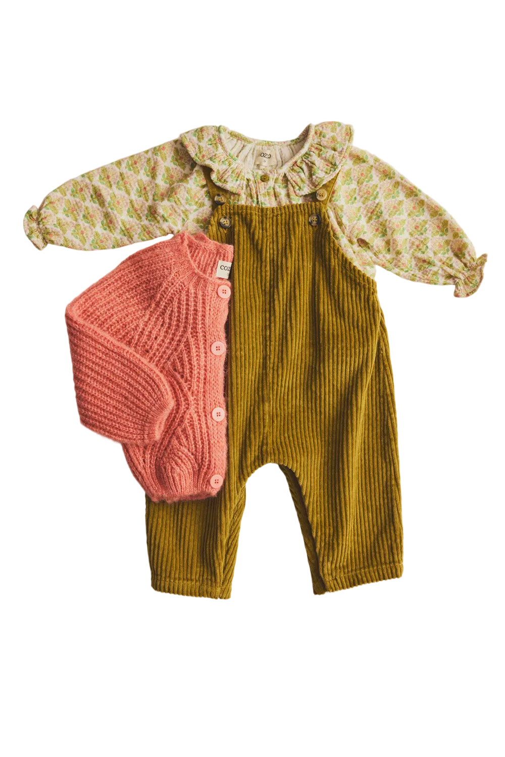 Children's outfit with floral blouse, pink knitted romper, and mustard yellow pants on a light background